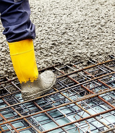 Beton fließt über Stahlträgermatte, welche auf Folie ausgelegt ist.