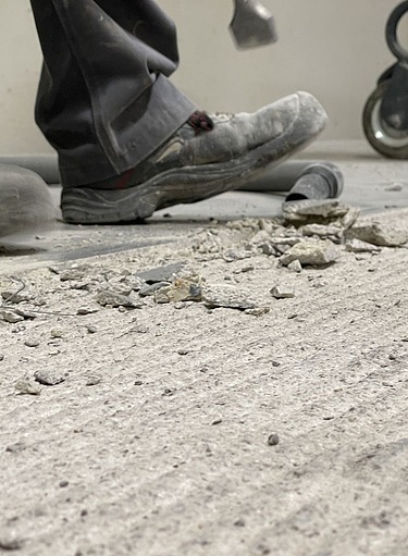 Sanierung eines beschädigten Betonbodens: Entfernen von losen Betonstücken und Vorbereitung für die Bodensanierung im Industriebereich.