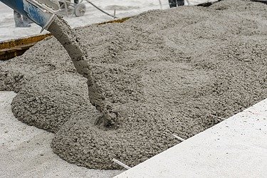Frisch gegossener Stahlfaserbeton wird auf einer Baustelle verteilt – robuste Industrieböden aus Stahlfaserbeton für hohe Belastungen in Produktions- und Lagerhallen.