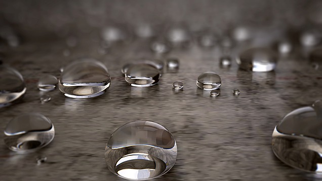 Nahaufnahme von Wassertröpfchen auf glatten, versiegelten Beton, der eine wasserabweisende Beschichtung aufweist.