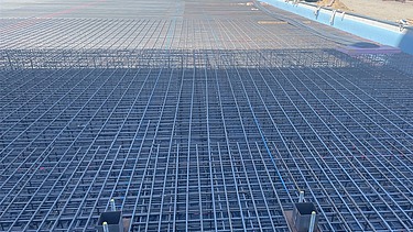 Großflächige Stahlbewehrung für eine Industriebodensohle im Hochregallagerbau, verlegte Bewehrungsmatten mit Einbauteilen vor dem Betonieren auf einer Baustelle