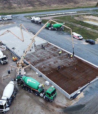 Mehrere moderne Laderampen an der Rückseite eines großen Industrie- oder Logistikgebäudes. Vor den Rampen befindet sich eine breite, saubere Betonfläche, die als Lade- und Rangierbereich für Lkw dient.