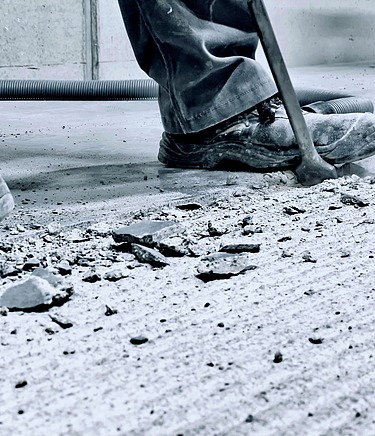 Arbeiter entfernt beschädigten Industrieboden.