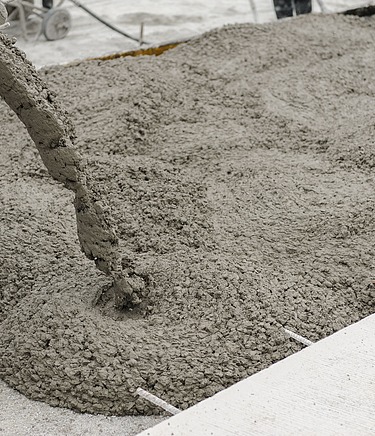 Frisch gegossener Stahlfaserbeton wird auf einer Baustelle verteilt – robuste Industrieböden aus Stahlfaserbeton für hohe Belastungen in Produktions- und Lagerhallen.