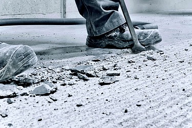 Arbeiter entfernt beschädigten Industrieboden.