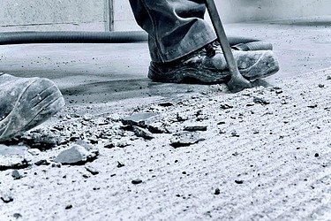 Arbeiter entfernt beschädigten Industrieboden.